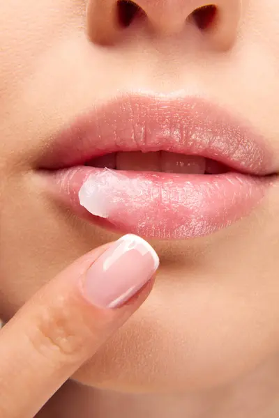 Perfect natural lip makeup. Close up photo of woman applying with finger hygienic lip balm. Moisturizing treatments for dry lips. Concept of beauty, make-up, cosmetology, spa, cosmetic products. Ad