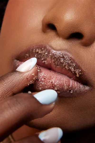 Closeup view of African-American woman with full lips covered in sugar. Exfoliate spa treatment for lips. Concept of beauty, make-up, cosmetology, spa treatments, cosmetic products. Ad