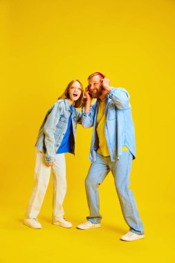 Baba kız, ebeveyn ve çocuk kot pantolon giyip tek kulaklıktan müzik dinleyerek eğleniyorlar. Ebeveynlik kavramı, çocukluk, aile, tarz, moda.
