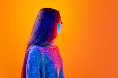 Sakin, çekici genç bayan, genç kız ve öğrencinin yan görünüm portresi. Neon ışıkta, filtrede farklı bir yöne bakıyor. Güzellik anlayışı, insani duygular, yüz ifadesi, moda. Ad