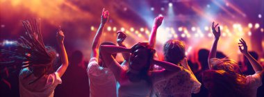 Pankart. Çekici gençlerden oluşan bir kalabalık, yaz müzik festivalindeki öğrenciler neon ışıkları altında dans edip şarkı söylüyorlar. Parti konsepti, festivaller, konserler, müzik ve dans, eğlence, macera.