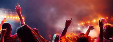 Kalabalık dans ediyor, sahne önünde en sevilen müzik grubunun konserinde neon ışıkta ellerini kaldırıyor. Parti kavramı, festivaller, konserler, müzik ve dans, tatiller, maceralar, duygular.