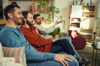 Bir grup arkadaş, erkekler evdeki oturma odasındaki kanepede oturup televizyon izlerken konuşup eğleniyorlar. Arkadaşlık kavramı, birliktelik, TV programı, online etkinlik, dinlenme ve rahatlama. Ad