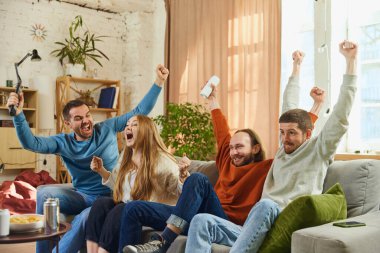 Bir grup mutlu ve neşeli genç, belirleyici futbol maçını izledi ve favori takım son dakikada gol attı. Arkadaşlık kavramı, birliktelik, TV programı, online etkinlik, eğlence.