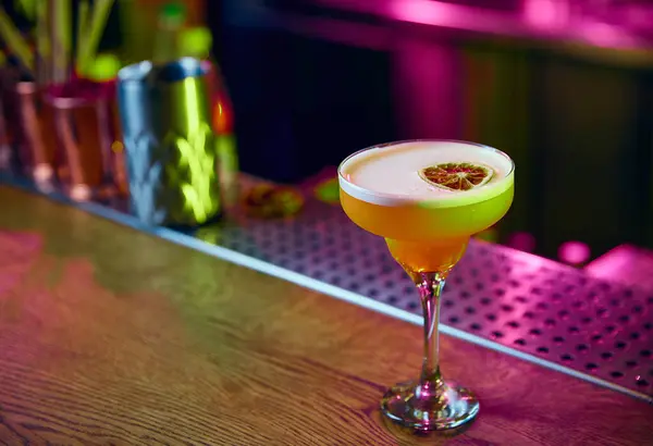 Angle view of fresh sweet and sour cocktail, alcohol drink decorated with dry citrus stands on bar counter at night club or restaurant. Concept of party time, night club, people lifestyle.