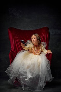 Sevimli küçük kraliçe, uzaktan kumandayla tahtta oturan ve klasik arka planda hangi TV programını izleyeceğini seçen kız. Tarihi yeniden yapılanma kavramı, çağların karşılaştırması, ortaçağ modası.