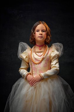 Ortaçağ insanı gibi giyinmiş eski moda elbiseli, esmer geçmişine karşı duran aksesuarlı küçük bir kızın portresi. Tarihi yeniden yapılanma kavramı, dönemlerin karşılaştırılması, duygular.