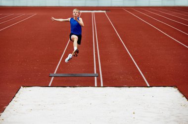 Sporcuların vücut dilleri havanın ortasında. Genç adam, profesyonel sporcu yerden sert bir şekilde itildi ve mükemmel uzun atlama yapmak için yükseğe uçtu. Spor anlayışı, şampiyonluk, motivasyon.