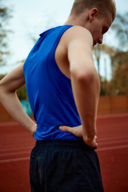 Kaslar gerildi, yaklaşan uzun atlama yarışmasına hazır. Şampiyonluktan önce spor sahasında ısınan bir adamın arka plan portresi. Spor, şampiyonluk, motivasyon, enerji kavramı.