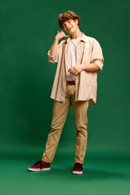 Genç bir adamın tam boy portresi, şık giyinmiş eski moda bir öğrenci ve yeşil stüdyo arka planında Bell Sing 'i gösteren pozlar. İnsan duyguları kavramı, yüz ifadesi, iş, öğrenim
