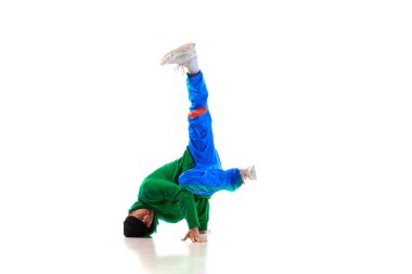 Genç, esnek, sportif, yeşil ve mavi formayla dans eden adam beyaz stüdyo arka planında dans ediyor. Eylem kavramı, sanat, güzellik, spor, gençlik. Dansçı breakdance figürleri gösteriyor