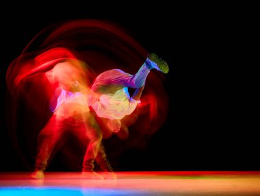 Genç atletik adam, break dans yapan hip-hop yapan B-boy, bir elinde breakdance, hareket bulanıklığıyla siyah arka planda bacaklarını kaldırıyor. Gençlik kültürü kavramı, aktif yaşam tarzı, yaratıcılık, sanat.