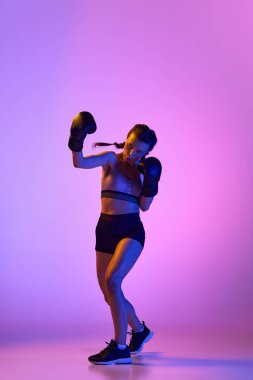 Kadın boksör, profesyonel MMA sporcusu, neon ışıktaki değişken arka plana karşı yapılan portrede görülen atletik maharet ve yoğunluk. Spor anlayışı, aktif yaşam tarzı, sağlık, rekabet.