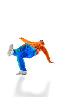 Şık giyimli bir adam, erkek, profesyonel dansçı serbest stil yapıyor, breakdance donuyor, beyaz arka plana yaslanıyor. Eylem kavramı, güzellik, spor, gençlik. Dansçı breakdance figürleri gösteriyor