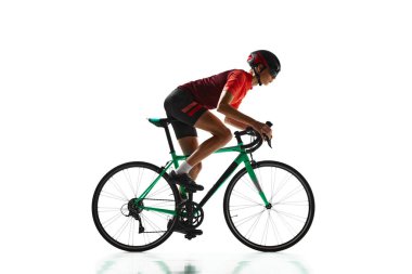 Konsantre genç adam, spor giyim ve kask süren bisiklet sporcusu, beyaz stüdyo arka planında izole edilmiş eğitim. Spor, eylem, rekabet, güç ve dayanıklılık kavramı, sağlık