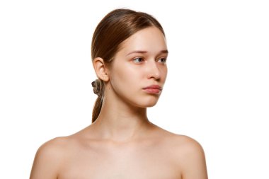 Genç, güzel, esmer, taze, parlak ciltli ve doğal makyajlı bir kız beyaz arka plana bakıyor. Cilt bakımı kozmetik tedavisi. Gençlik kavramı, sağlıklı yaşam tarzı. Ad