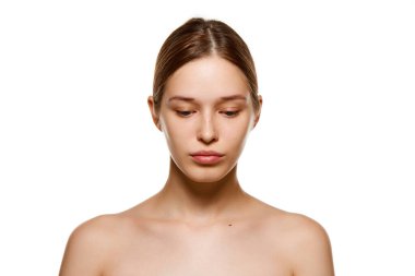 Çıplak omuzlu, tertemiz derili, izole edilmiş beyaz stüdyo geçmişine bakan güzel bir genç kızın portresi. Cilt bakımı kozmetik tedavisi. Gençlik kavramı, doğal güzellik. Ad