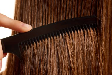 Esmer saçı yakından çek. Uzun, ipeksi düz saçlarını tarayan esmer saçlı genç bir manken. Saç bakımı kozmetik tedavisi. Kavramsal gençlik, doğal güzellik, sağlıklı yaşam tarzı. Ad