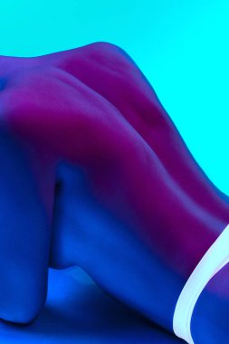 Hassas, çekici, çıplak kadın vücudunun bir parçası, neon ışıkta mavi arka planda rahatlama. Vücut estetiği, sanat, güzellik, şehvet, çıplaklık, özgürlük, kabullenme kavramı