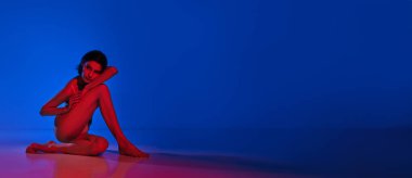 Pankart. Modern cazibeyle ışıldıyor. Kadın iç çamaşırı giymiş yerde poz veriyor ve neonlu arka plana bakıyor. Uzayı kopyala Kadın sağlığı, sağlık, kendini ifade etme kavramı.