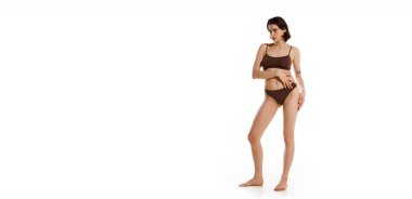 Güzellik ve kendine güven. Kahverengi iç çamaşırlı genç bir kadın beyaz stüdyo arka planında zarifçe poz veriyor. Mesajın için de olumsuz bir yer var. Kadın sağlığı, kadınlık, sağlık kavramı.