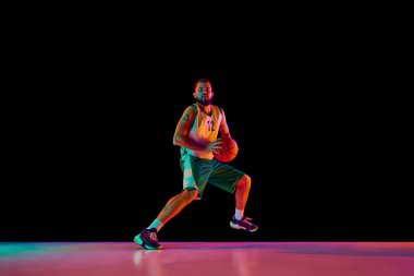 Basketbolcu, atletik adam mükemmel smaç basıyor, resim gücü ve neon ışıkta siyah arka plana karşı hassasiyet gösteriyor. Spor anlayışı, hobi, aktif yaşam tarzı. Boşluğu kopyala, ad