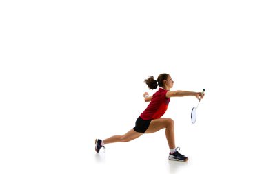 Genç, çekici bayan badminton oyuncusunun dinamik portresi el değmemiş beyaz arka plana karşı antrenman sırasında hareket halindeki atletizmini yakalıyor. Spor anlayışı, güç ve güç, eylem.