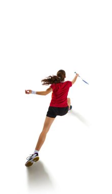 Fit ve çekici genç bir kadının dinamik portresi badminton yeteneklerini eylem halinde sergiliyor, saldırıyı ve beyaz arka plana karşı savunmayı özetliyor. Spor, güç ve güç kavramı. Ad