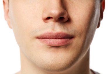 İyi bakımlı, tıraşlı, bakımlı ve beyaz arka planda tam nemlendirilmiş dudakları olan genç bir adamın yakın doğrama portresi. Güzellik, temizlik ve vücut bakımı kavramı.