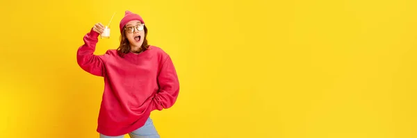 stock image Banner. Young attractive happy lady holds milk cocktail with straw against yellow background with negative space to insert your text. Concept of fashion and style, traveling, culture, fun and joy.