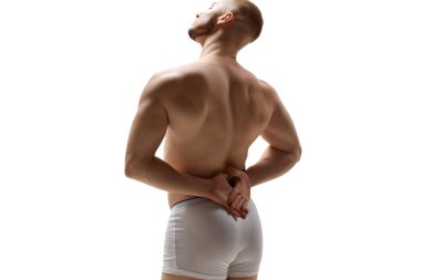 Arka planda çıplak atletik genç adamın beyaz stüdyo arka planına karşı kaslarını ve ellerini gösteren fotoğrafı var. Erkek sağlığı, güzellik, vücut ve cilt bakımı, spor anlayışı. Vücut sanatı