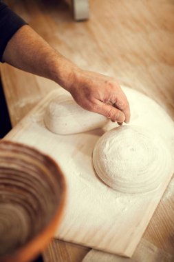 Tahta kesme tahtasından para kazanan biri. Beyaz ve iyi pişmiş hamur işi. Elini yavaşça hamura bastır ve parmaklarını aç. Doğa, yemek, diyet, yemek pişirme, fırın.