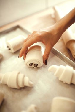 Yakın çekim, kadın eli hamur işleri, kruvasanlar ve çikolatalı ekmekleri seçici odak noktasında serer. Doğa, yemek, diyet, yemek, beslenme, fırın, Fransız tatlı tarifleri.