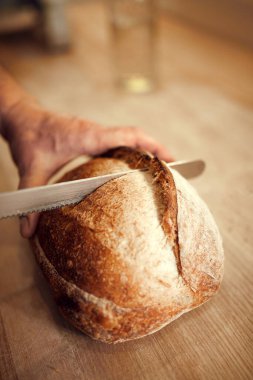 Fırıncı adam, ahşap kesim tahtasından kesilen aşçı. Az önce hazırlandı. Lezzetli, kıtır kıtır ekmekli bir somun ekmek. Yemek, fırın, gelenek ve yenilik kavramı, tarif.