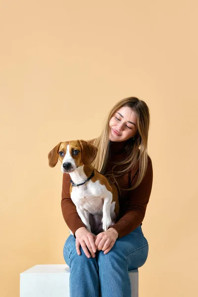 Portrait of cute Beagle on hands of attractive happy smiling young woman. Friendship between dog and human. Concept of animal, pet lover, friendship, domestic life, companionship. Ad