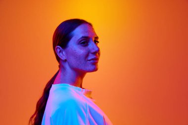 Side view portrait of young attractive lady looking away against gradient orange-yellow background with copy space for text. Concept of beauty, youth, human emotions, self-expression, lifestyle. Ad
