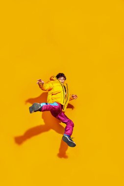 Havalı bir uçuş. Esnek, modaya uygun giyinmiş, kışlık kıyafetler ve sarı gözlüklü bir genç. Moda ve güzellik kavramı, modern tarz, alışveriş, satış sezonu.