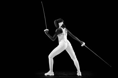 İki kılıç kullanan sporcunun çarpıcı profili, güç ve zarafet yayma, atletizm ve siyah stüdyo geçmişine karşı bağlılık. Profesyonel spor ve hobi kavramı, şampiyonluk. Ad