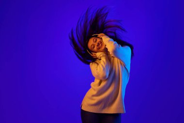 Yükseltilmiş Enerji. Kulaklıklı kızın dinamik portresi enerjik bir şekilde kafasını müziğin ritmine sallıyor ve saçları hareketli bir şekilde gelişiyor. Güzellik ve moda kavramı, kendini ifade etme, rahatlatıcı..