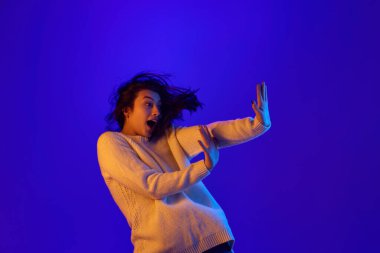 Olumsuz dur. Genç bir kadının dinamik portresi ellerini dur işareti olarak öne koydu ve mavi eğimli arka plana doğru hareket etti. Klişelere ya da aile içi şiddete hayır deme kavramı.