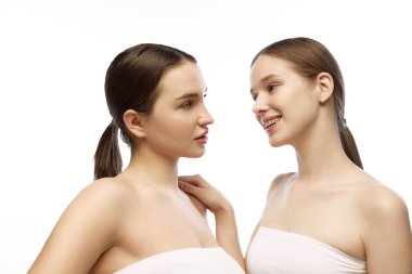 Ciltlerinin berraklığını vurgulamak için doğal makyaj yapan iki kadın ve beyaz arka planda birbirlerine bakan güzelliklerinin ince özelliklerini vurgulamak için. Dermatoloji kavramı, cilt bakımı rutinleri.