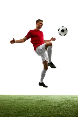 Hedefe Yükseliş. Profesyonel futbolcu, saf beyaz ve yemyeşil çimenlerin arka planına karşı rakip kapıları hedefleyerek topa vuruyor. Spor oyunları kavramı, enerji, eşleşme, hareket.