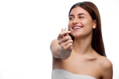 Seçici odaklanma. Doğal olarak uzun, ipeksi ve sağlıklı saçları olan güzel bir kadın kameraya saç bakım yağı kapsülünü gösteriyor. Organik güzellik kozmetik, spa prosedürleri, vücut bakımı kavramı.