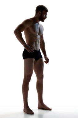 Beyaz stüdyo arka planında siyah iç çamaşırlarıyla poz veren genç, atletik bir adamın vücut ölçülerinde fotoğrafı. Pürüzsüz ve mükemmel bir ten. Doğal güzellik kavramı, estetik beden, erkek sağlığı, erkeklik..