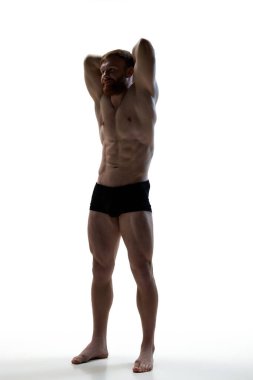 Genç erkek modelin atletik kıvrımları. Genç adamın portresi güçlü gövdesini beyaz stüdyo arka planına karşı gösterdi. Doğal güzellik kavramı, estetik beden, erkek sağlığı, erkeklik..