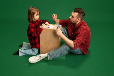 Kızına yeşil stüdyo geçmişine karşı resim yapmayı öğreten bir adam. Uluslararası Mutluluk Günü kavramı, çocukluk ve ebeveynlik, olumlu duygular, boş zaman aktiviteleri. Ad