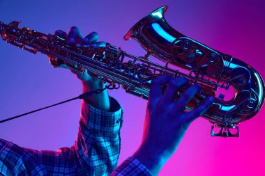 Jazzman 'ın saksafon çalarken çekilen portresi neon ışıkta mavi-pembe arkaplana karşı. Caz melodileri. Klasik müzik enstrümanı, konserler ve festivaller kavramı. Ad