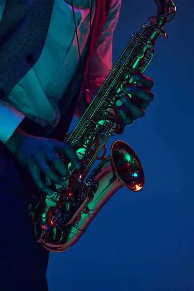Jazz in modern music. Close-up cropped photo of young handsome man playing saxophone in neon light. Gel portraits. Concept of classical musical instrument, concerts and festivals. Ad