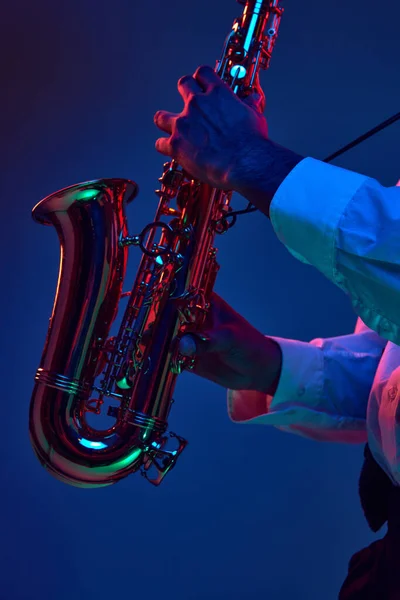Major and Minor. Cropped photo of African-American man, holds Alto Sax and improvises jazz melodies in mixed neon lights. Concept of classical musical instrument, concerts and festivals. Ad
