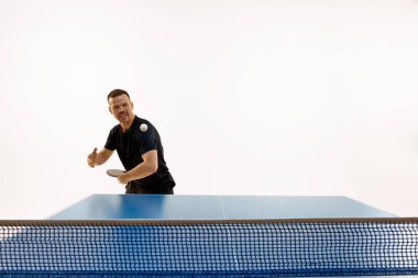 Siyah spor giyimli konsantre masa tenisçisinin portresi beyaz arka planda yüksek enerjili rallide. Profesyonel spor, dinamik ve enerji kavramı, şampiyonluk, turnuva. Ad.